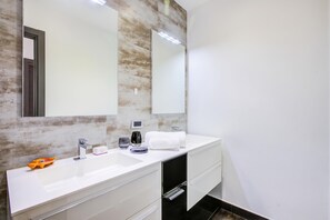 A modern bathroom with a large mirror, two sinks, a towel, and a coffee maker. - Asia Apartment 2BR in Laveno Center (Laveno Mombello)