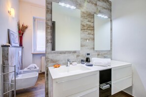 Ein modernes Badezimmer mit einem Waschbecken-Doppelplatz, einer Toilette und einem großen Spiegel.