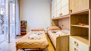 Ein Zimmer mit zwei Betten, einem Holzschrank und einem Fenster mit Blick nach draußen.