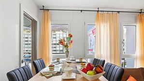 A dining area with a wooden table, black chairs, a vase with flowers, and a bowl of fruit. - Locarno Centro Apartment 2BR With Private Garage (Locarno)