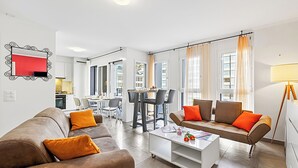 A modern living room with a brown sofa set, a white coffee table, and a dining area with a table and chairs. - Locarno Centro Apartment 2BR With Private Garage (Locarno)