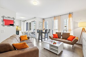 Ein modernes Wohnzimmer mit einer Sofagarnitur, einem Couchtisch und einem Essbereich mit Stühlen und einem Tisch.