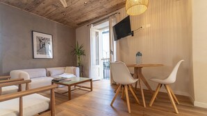 Una sala de estar moderna con techo de madera, un sofá, una mesa de centro, dos sillones, un televisor y una planta en maceta.