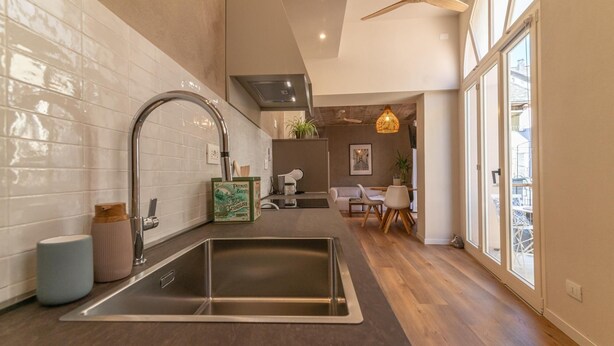 Una cocina moderna con un lavamanos de acero inoxidable, un ventilador de techo y vistas al área de estar.