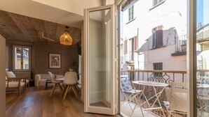 Una sala de estar moderna con techo de madera, un comedor con mesa y sillas, y un balcón con una mesa y sillas.
