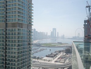 A high-rise building with multiple balconies overlooking a marina and city skyline. - Beachfront Marina Skyline Views (Dubai)