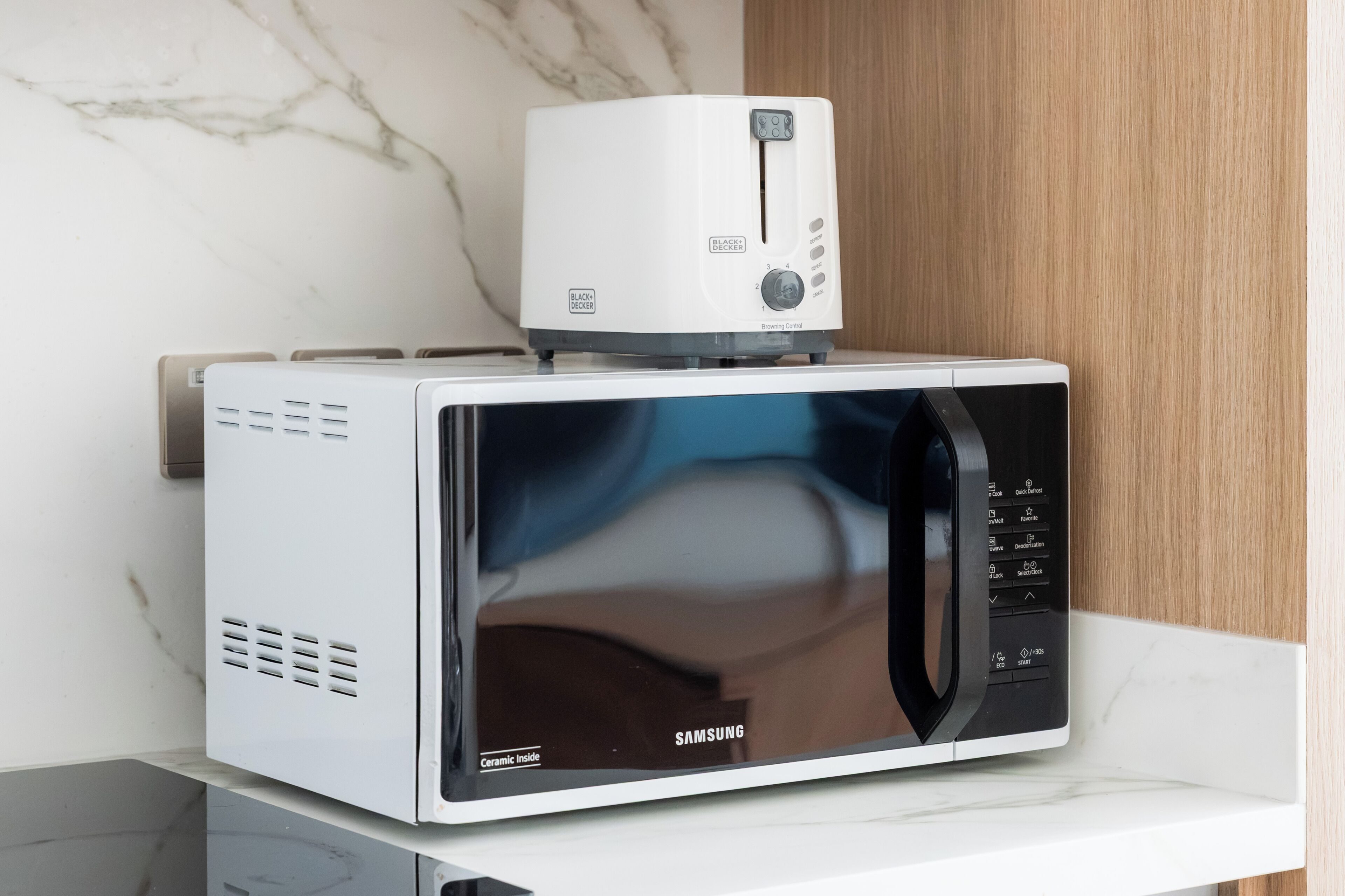 Un horno microondas con panel de control y pantalla digital, sobre una encimera blanca.