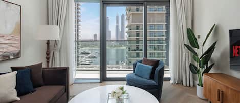 A modern living room with a large window, a sofa, a coffee table, and a TV.