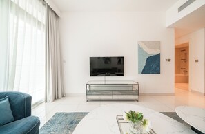 Un salon moderne avec un téléviseur à écran plat, une vitrine, un canapé bleu et une table basse en marbre.