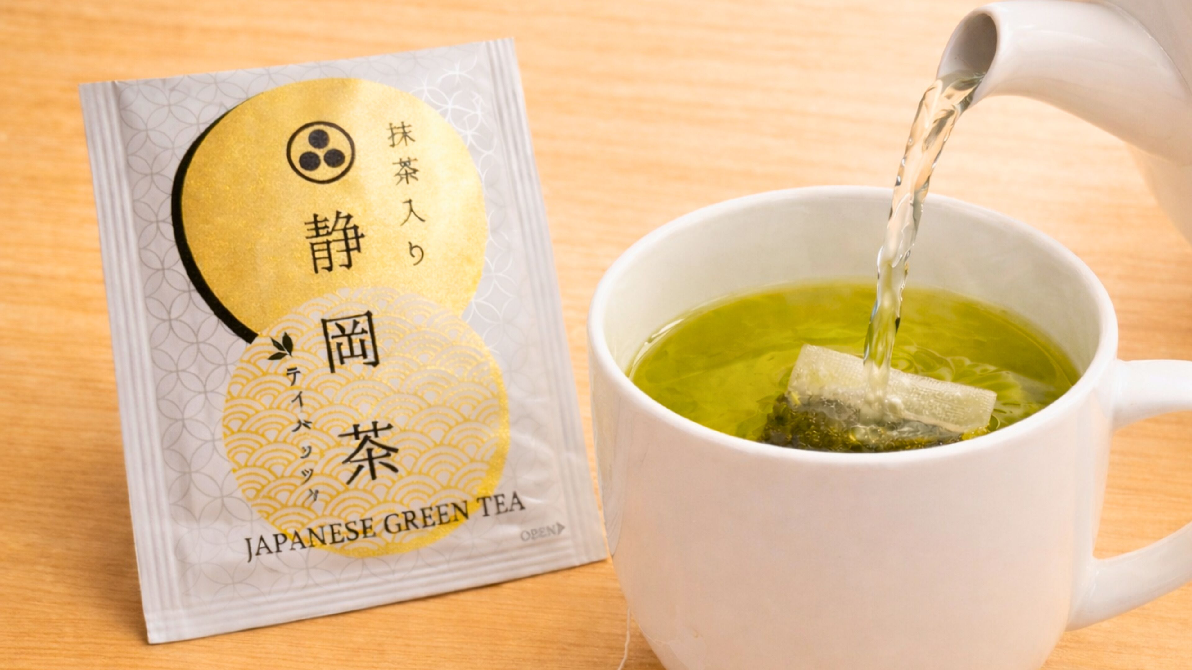 Un paquet de thé vert japonais et une tasse de thé versée à l’intérieur.