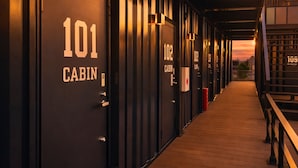 A row of cabins numbered 101 to 109, with a wooden walkway leading to a sunset view. - Hotel Cradle Cabin TANASHI (Nishitokyo)