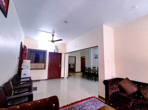 A living room with a sofa, a coffee table, and a dining area with chairs and a table.