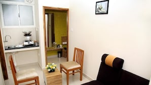Um espaço de estar compacto com cozinha compacta, uma cadeira de madeira, um sofá e uma mesa com um arranjo de flores.