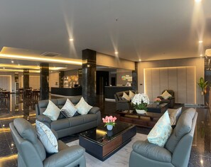 A modern hotel lobby with a reception desk, seating area with sofas and armchairs, and a bar. - The Quadrant Ocarina Hotel (Batam)