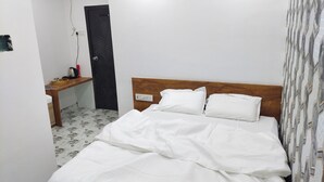 Una habitación pequeña y limpia, con una cama, un escritorio y una puerta.