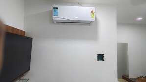 Una habitación con aire acondicionado, televisor de pantalla plana y un panel de madera en la pared izquierda.