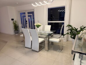 Un comedor moderno con una mesa de vidrio, sillas blancas y una planta en maceta.