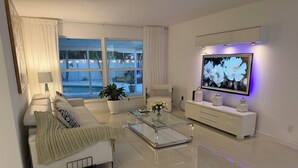 A modern living room with a sofa, coffee table, TV, and a large window.