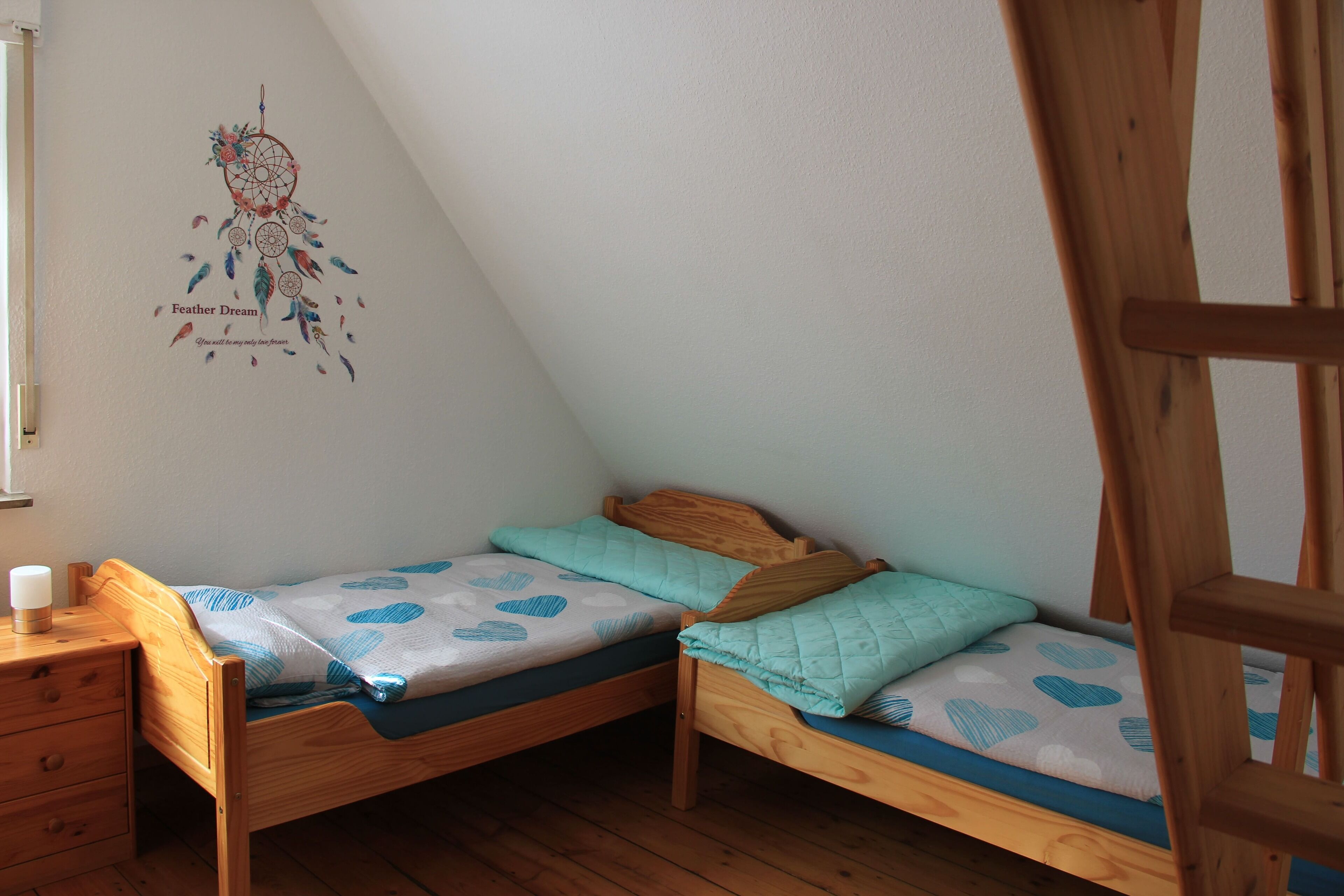 Un dormitorio pequeño y acogedor con dos camas de madera, una mesita de noche y un adorno en la pared.