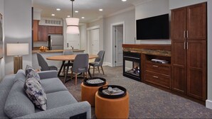 Ein modernes Wohnzimmer mit grauem Sofa, einem Esstisch mit Stühlen, einem Kamin und einem an der Wand montierten Fernseher.