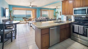 A kitchen with wooden cabinets, a stainless steel dishwasher, and a microwave. - Seaside Serenity at Sonoran Spa N704 (Puerto Peñasco)