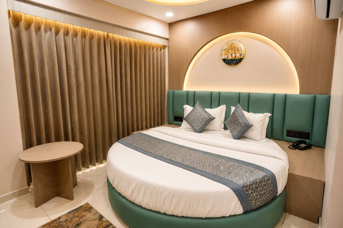 A modern hotel room with a curved bed, a round wall-mounted light fixture, a telephone, and a small round table.