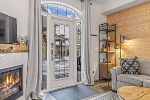 Un salon chaleureux avec une cheminée, un mur en bois, un canapé et une bibliothèque.