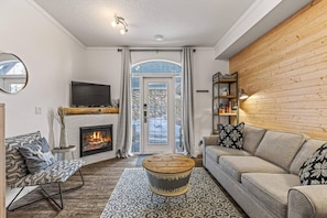 Un salon moderne avec une cheminée, un téléviseur et un coin salon confortable.