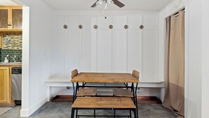 Un'area pranzo con un tavolo e panche in legno, una ventola a soffitto e un muro bianco con ganci.