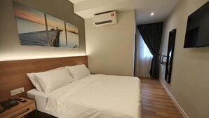 Habitación de hotel con cama, mesita de noche, televisión montada en la pared y un cuadro de un atardecer sobre un muelle.