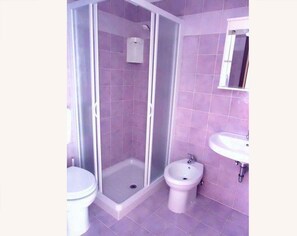 Un baño con ducha de vidrio, inodoro y bidé.