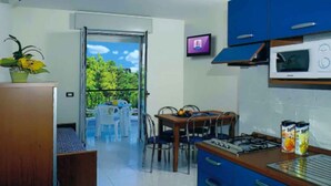 Eine moderne Küche mit blauen Schränken, einer Mikrowelle und einem Essbereich mit Tisch und Stühlen.
