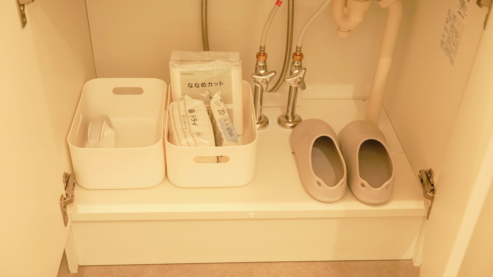 Un baño con lavamanos blanco, espejo, toallero y un par de zapatillas.
