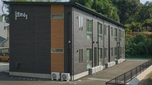 A modern building with a dark facade, large windows, and a series of air conditioning units on the ground level. - Opt Kuamaoto Mashiki (Mashiki)
