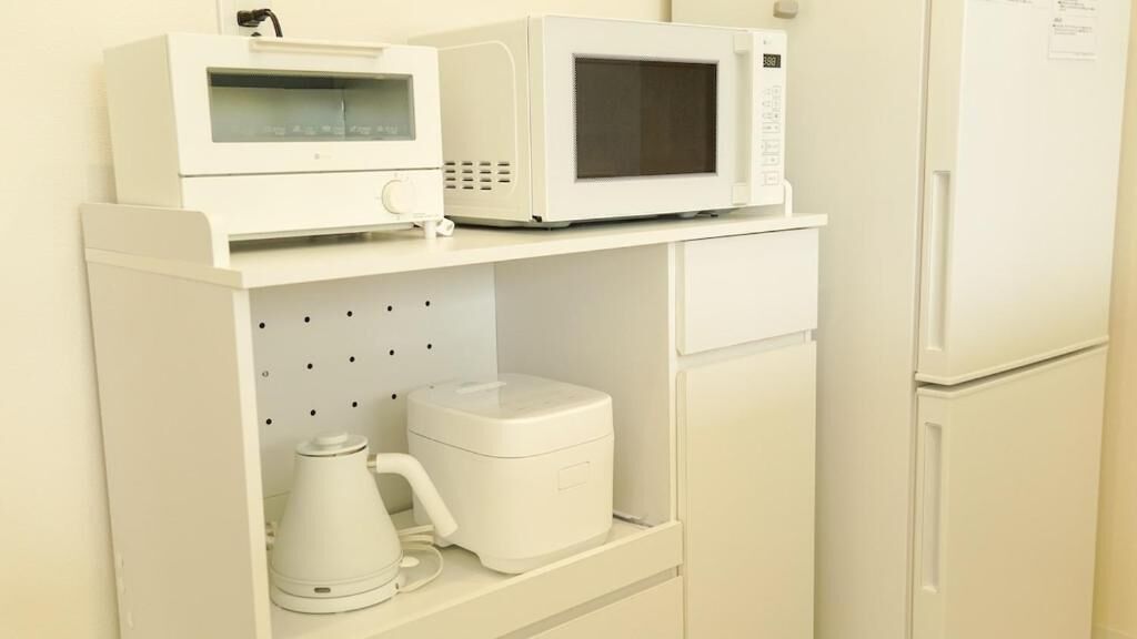 Een kitchenette met een magnetron, koffiezetapparaat en een kleine koelkast.