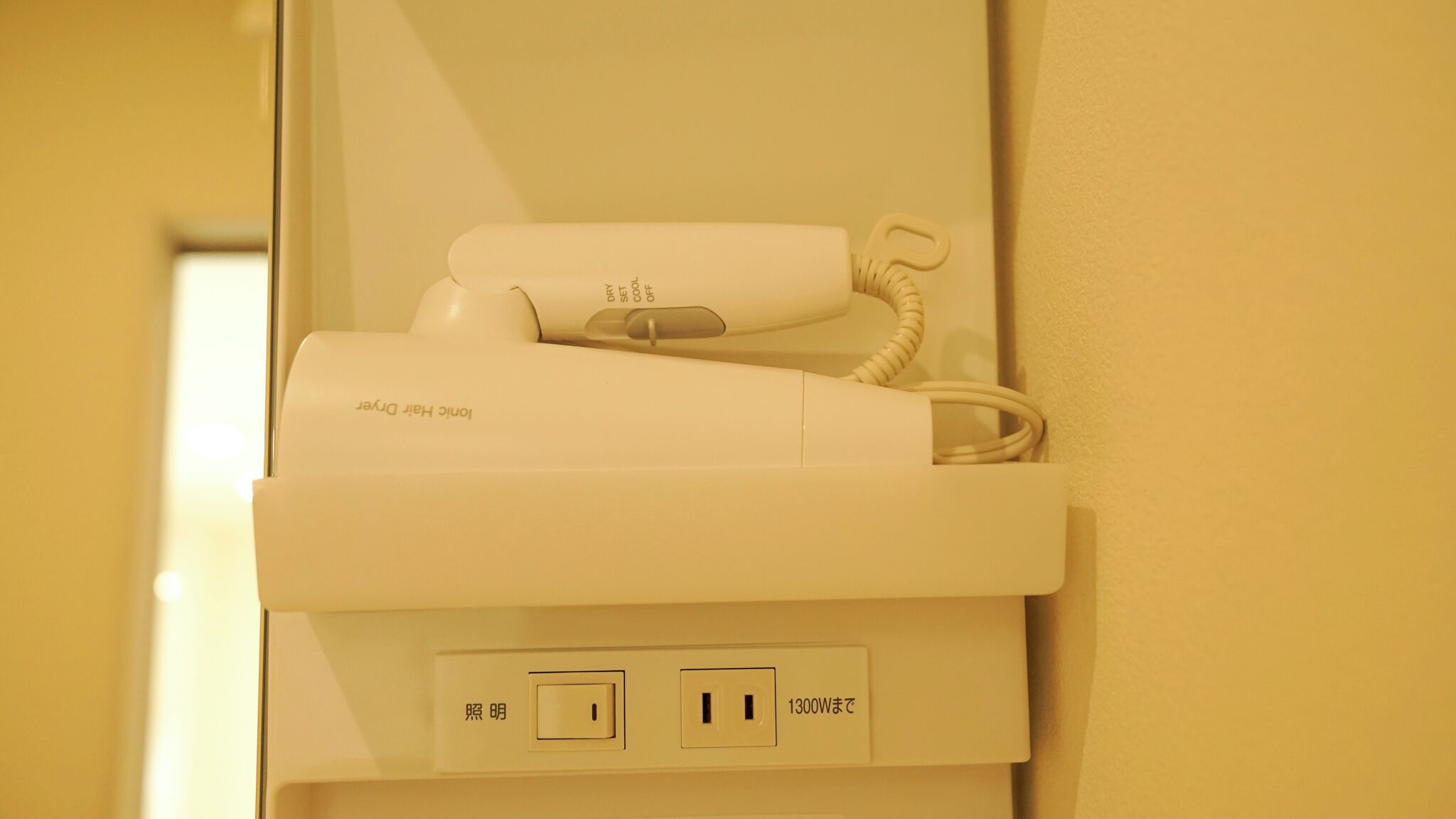 Ein weißes Telefon mit Kabel, das in eine Steckdose gesteckt ist, mit japanischem Text zur Kennzeichnung von Strom und einer 1300W-Leistungsbegrenzung.