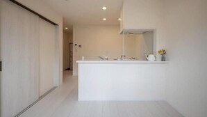 A modern bathroom with a white vanity, a mirror, and a small shelf with toiletries. - Opt Kuamaoto Mashiki (Mashiki)