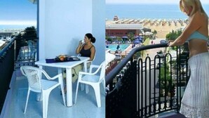 A balcony with a table and chairs, overlooking a pool and beach area. - Holiday apartment with air conditioning, balcony and pool (Bibione)