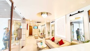 A modern hotel lobby with a reception desk, seating area, and a large window. - Hotel RG Residency (Varanasi)