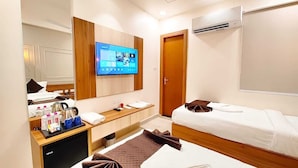 A hotel room with two beds, a TV, a desk with toiletries, and a wardrobe. - Hotel RG Residency (Varanasi)