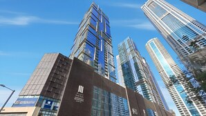 A modern building with a prominent entrance and multiple high-rise buildings in the background. - Deluxe Marina Gate Suite w/ Sea & Ain Dubai View (Dubai)