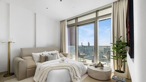 A modern bedroom with a large window, a sofa, a round coffee table, and a potted plant. - Deluxe Marina Gate Suite w/ Sea & Ain Dubai View (Dubai)