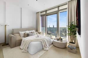 A modern bedroom with a large window, a sofa, a round coffee table, and a potted plant. - Deluxe Marina Gate Suite w/ Sea & Ain Dubai View (Dubai)