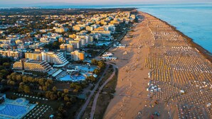 An aerial view of a coastal city with a large beach area and dense urban development. - Holiday apartment with air conditioning, balcony and pool (Bibione)