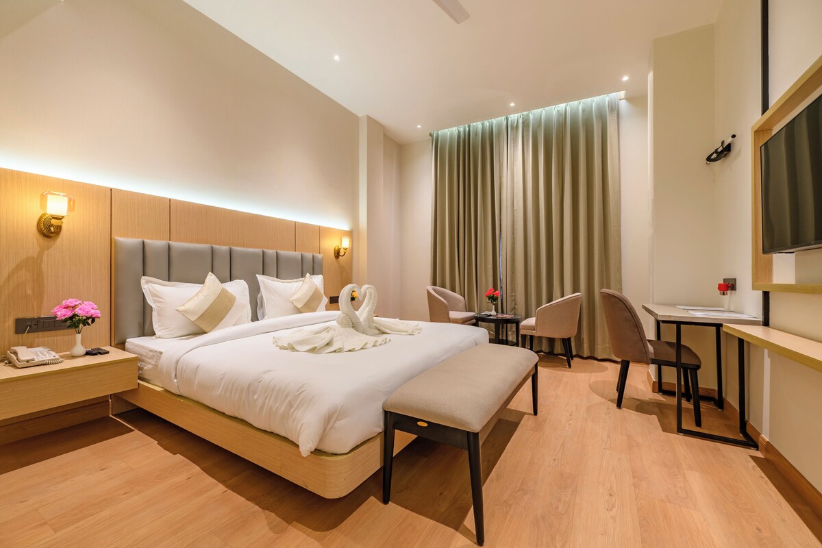 Habitació d'hotel moderna amb un llit gran, taules de nit, escriptori, cadira i televisió.