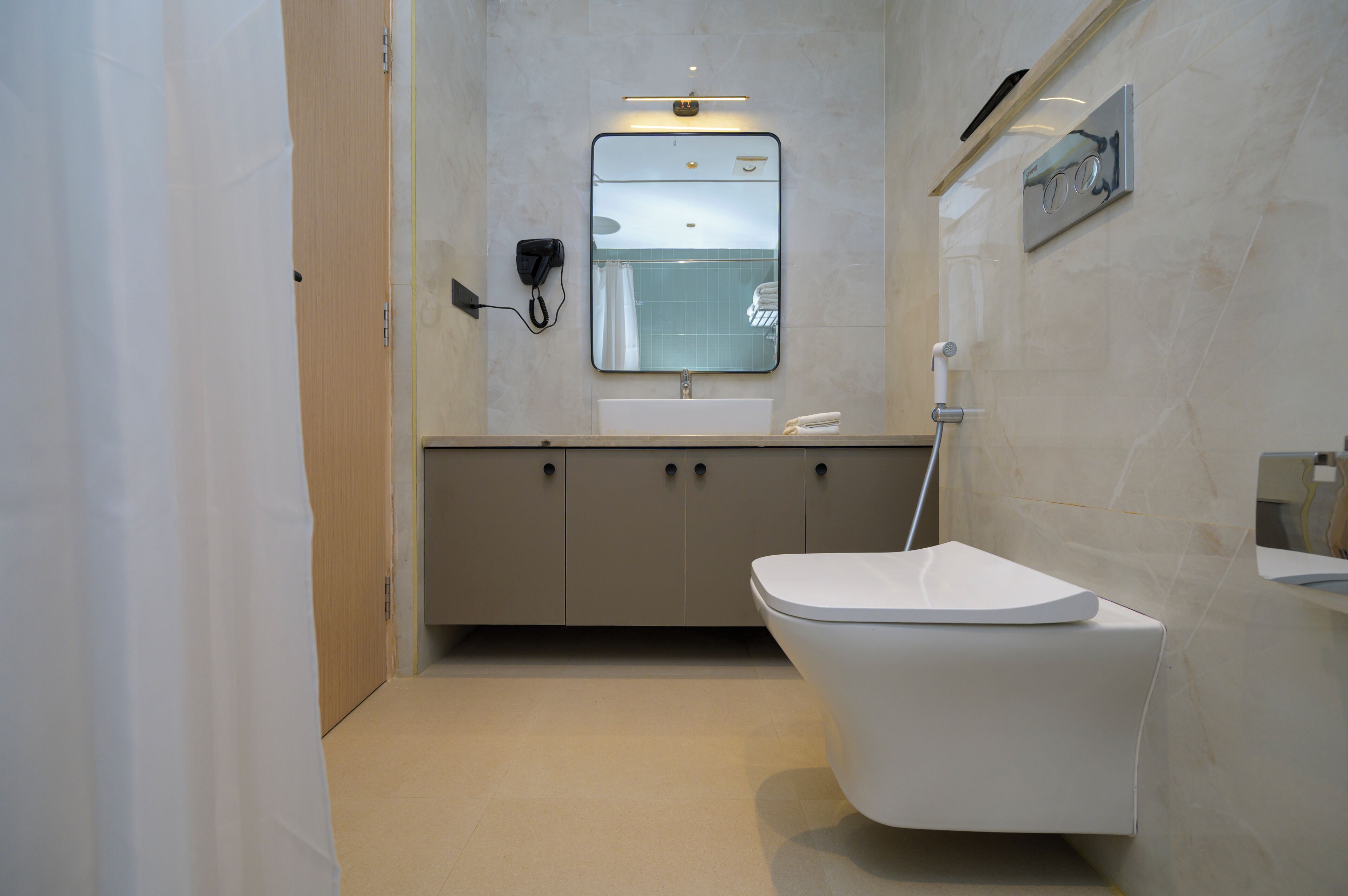 A modern bathroom with a toilet, sink, and mirror.