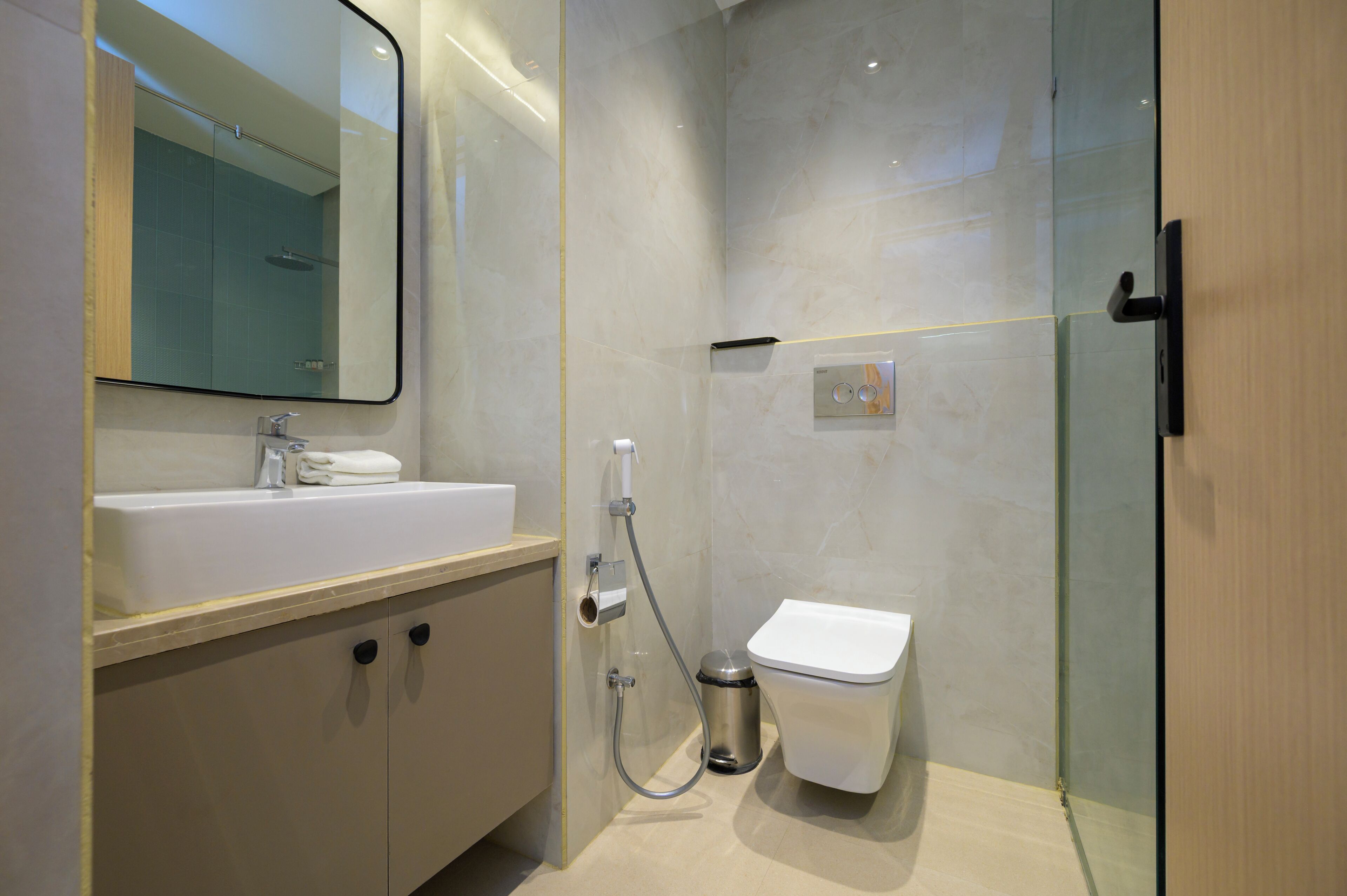 Un baño moderno con lavamanos, espejo, inodoro y ducha.