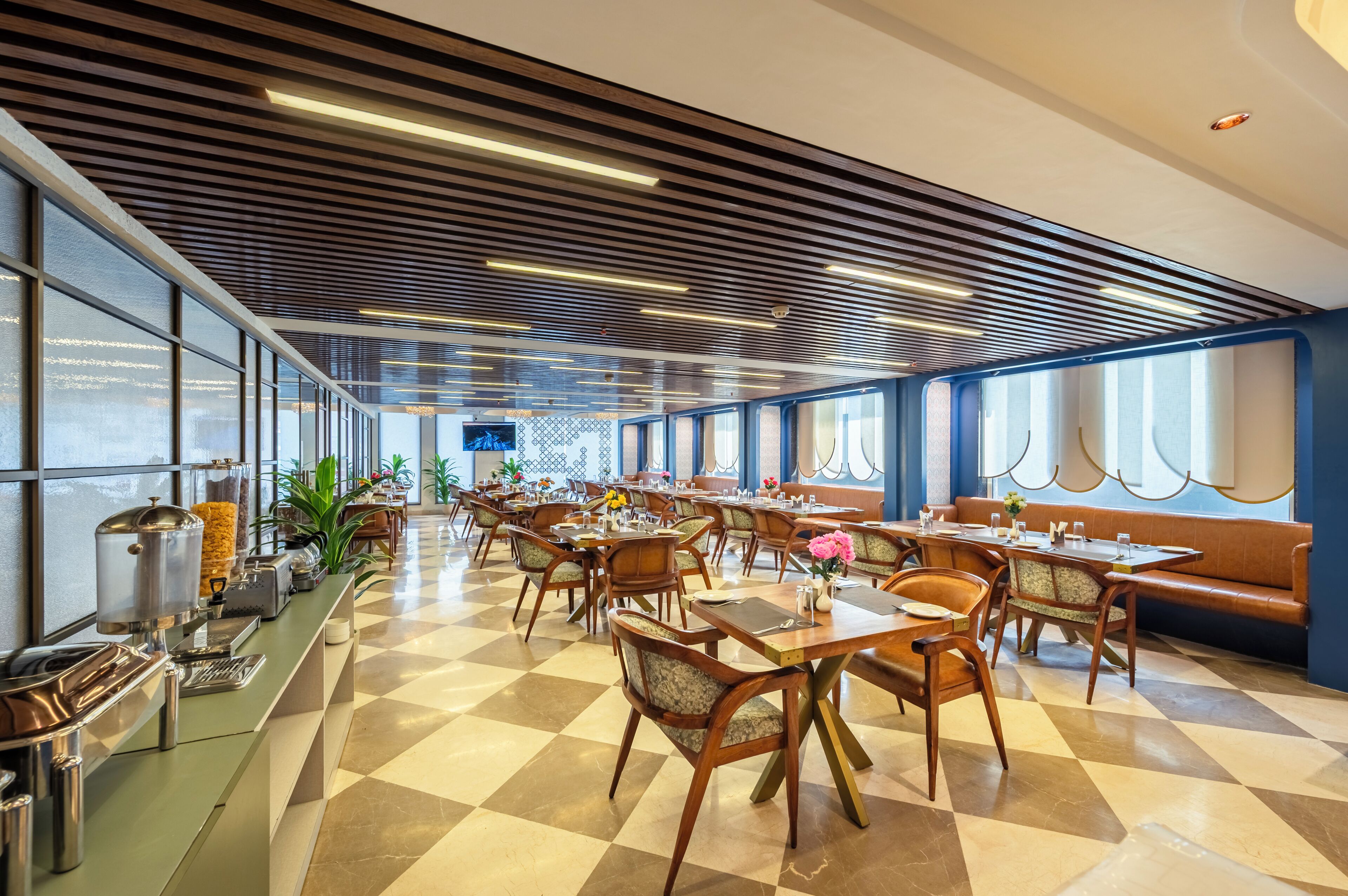 A spacious dining area with a checkered floor, wooden chairs, and a buffet line.