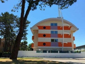 Un immeuble à plusieurs étages doté d’un toit incurvé, et agrémenté d’une série de fenêtres et de balcons.