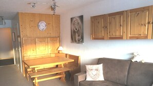 Une pièce comprenant une table à manger en bois, des bancs, un canapé et une horloge murale.